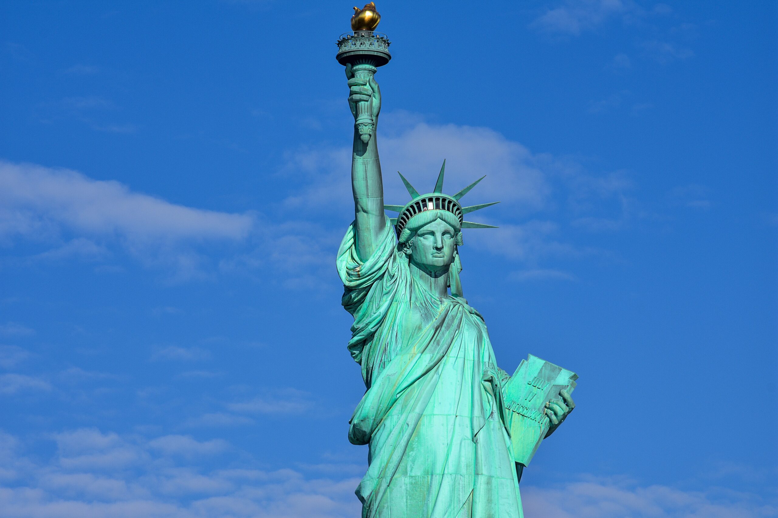 Statue of Liberty standing tall with blue skies, representing freedom and the American immigration dream